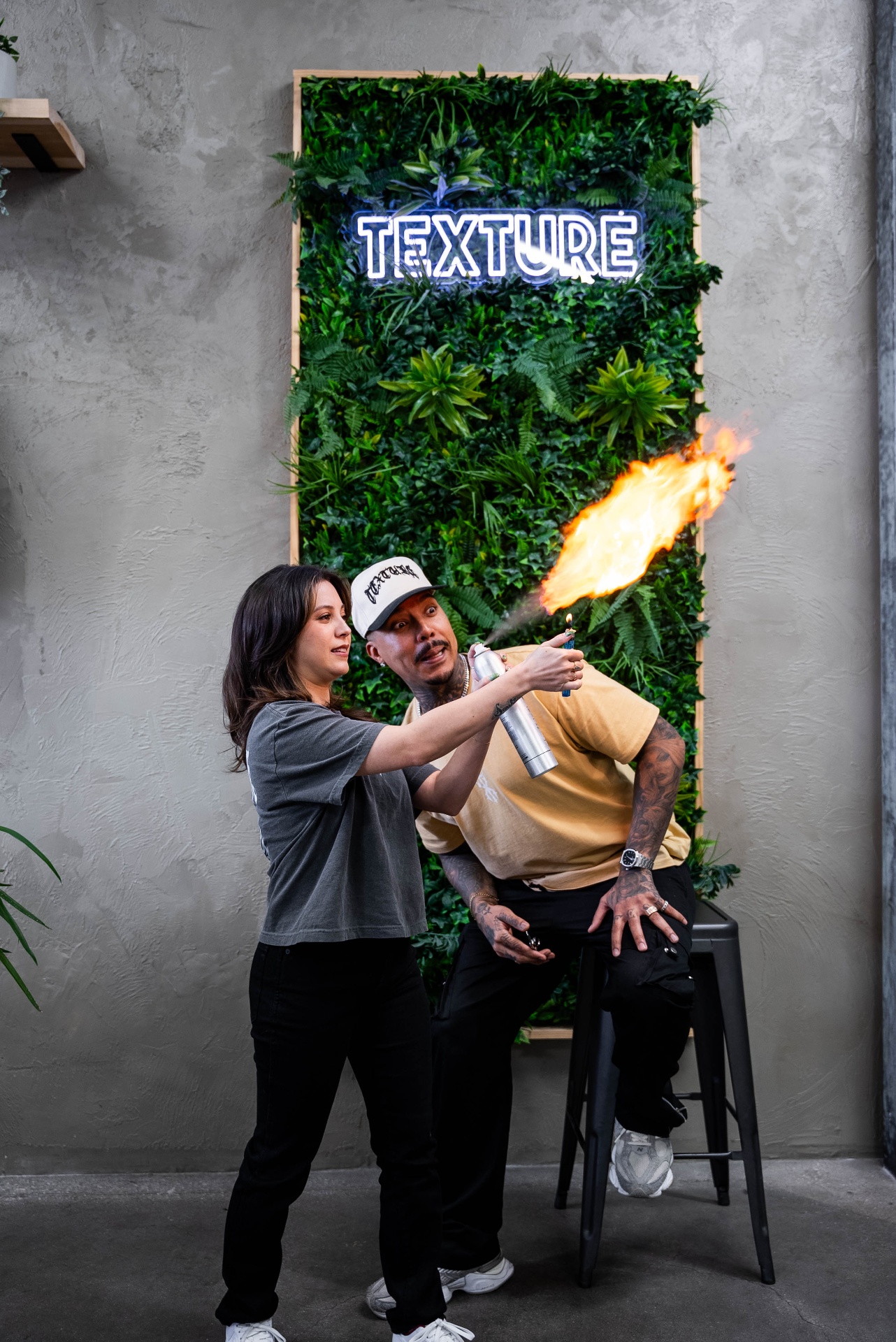 Texture Barbershop brand photo — stylist igniting hairspray in front of the shop's neon logo, Las Vegas