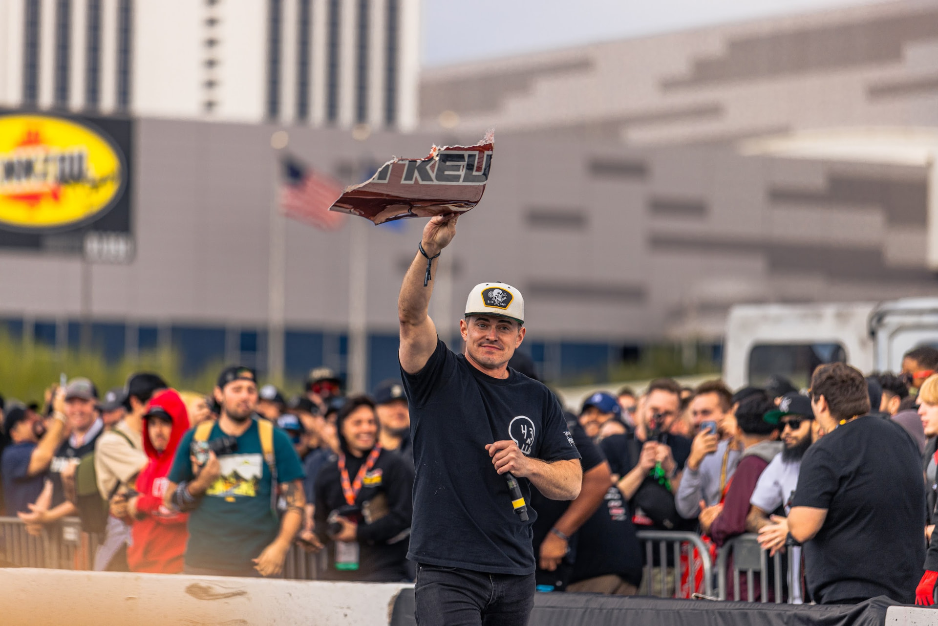 Event host holding up a shredded tire tread in front of the SEMA Ignited crowd in Las Vegas