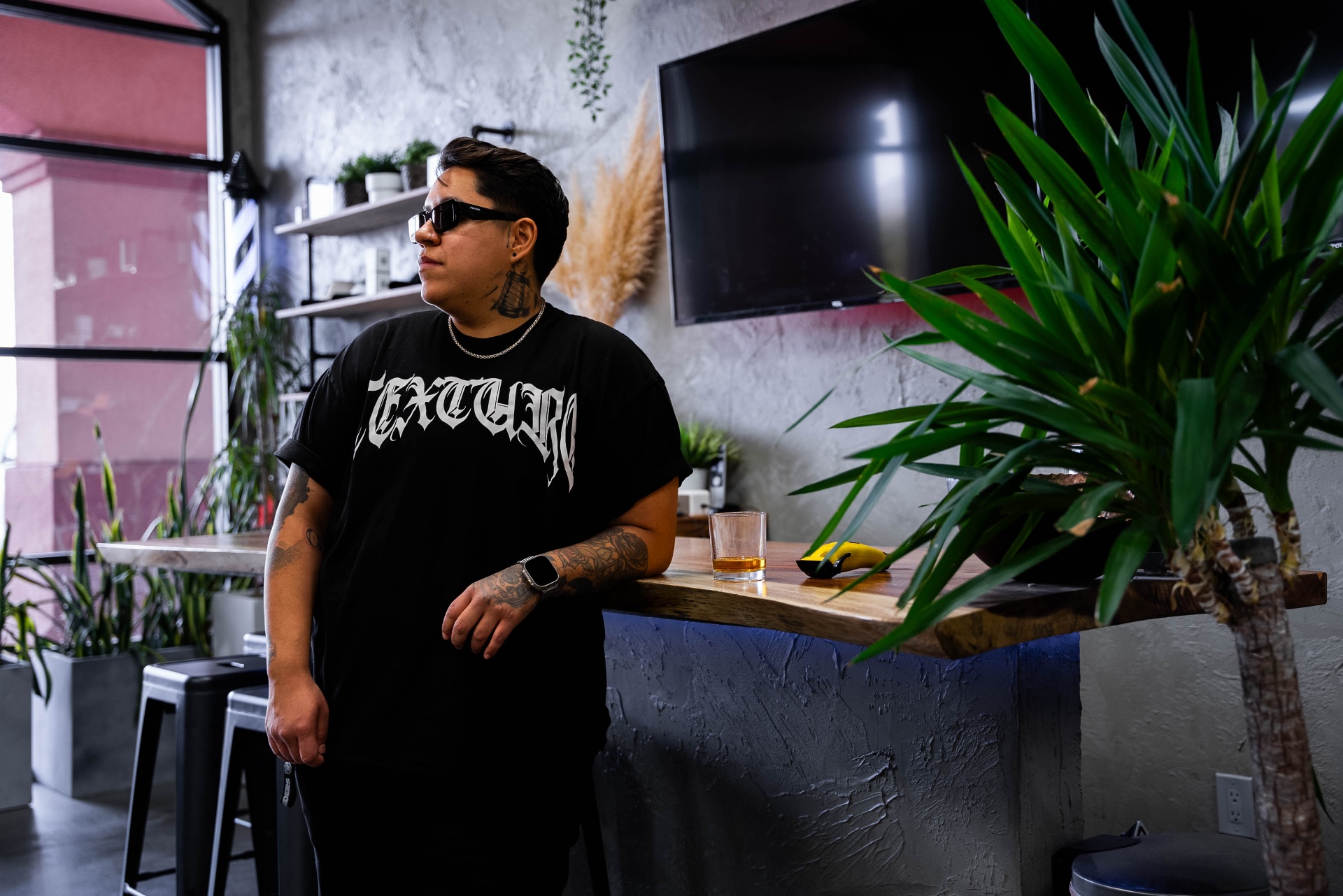 Texture Barbershop barber portrait leaning against the live-edge bar wearing a branded tee, Las Vegas
