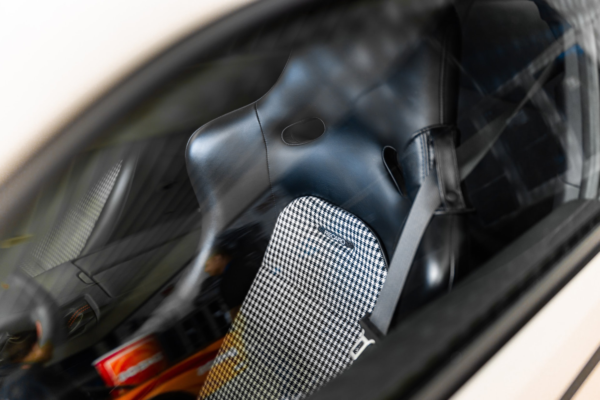 Close up of a Recaro houndstooth bucket seat and harness shot through the window of a show car at the SEMA Show
