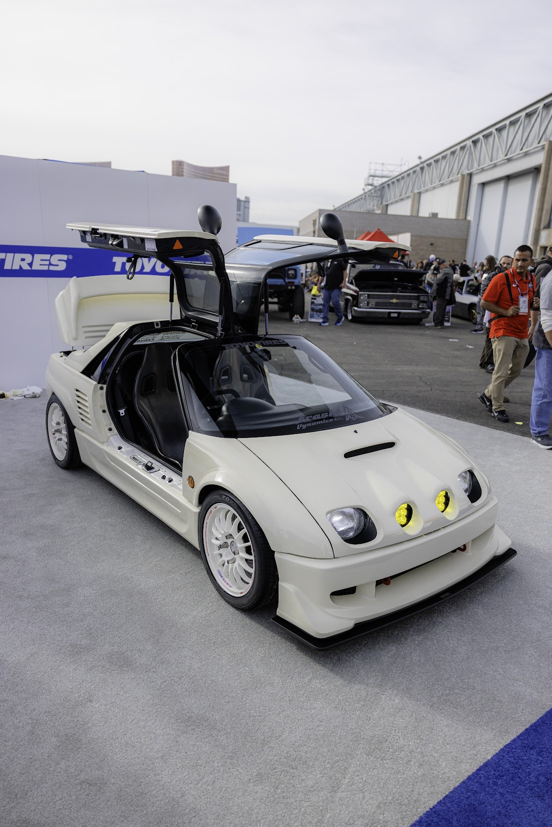 White Mazda Autozam AZ-1 with gullwing doors open on a Toyo Tires display carpet at the SEMA Show in Las Vegas