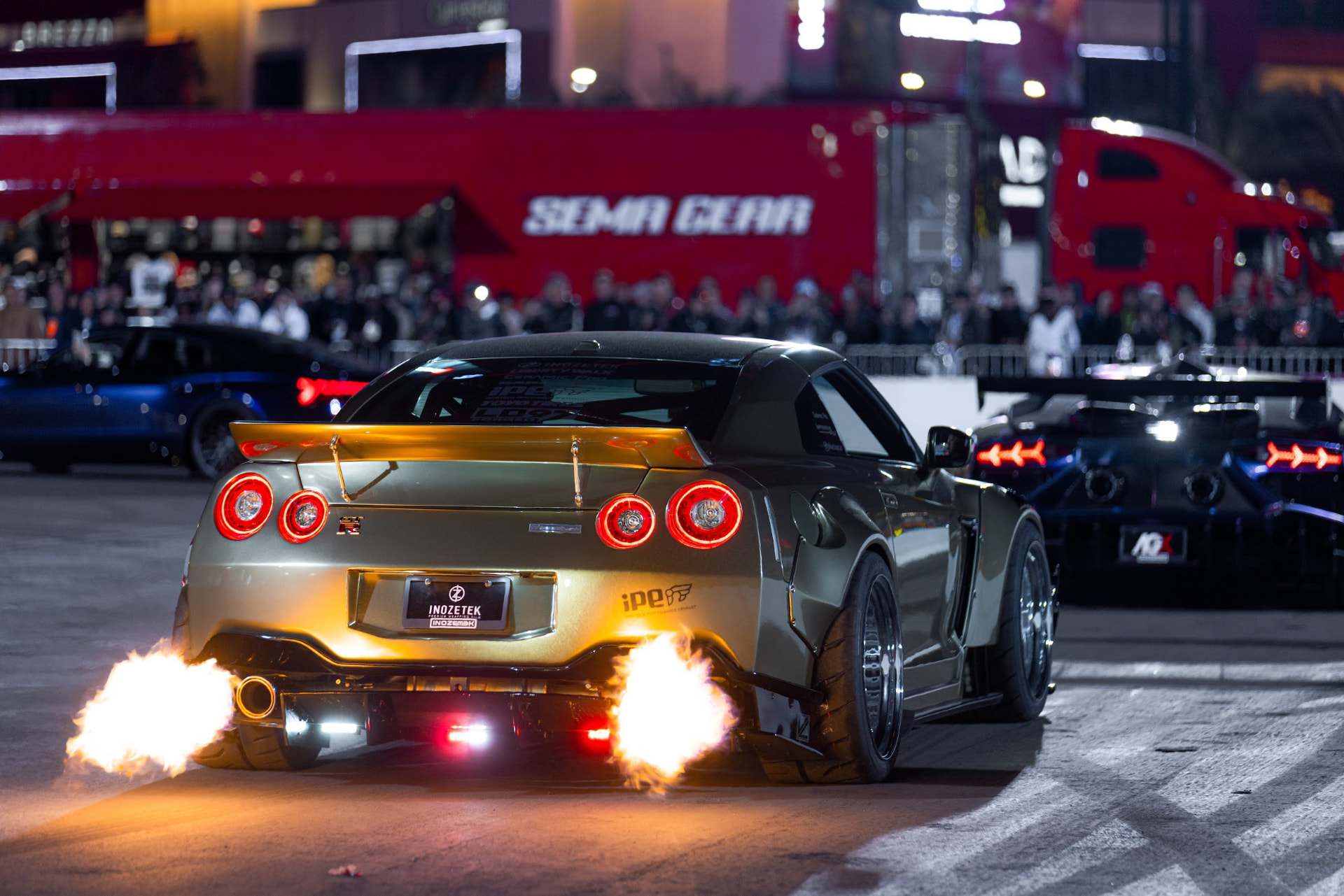 Gold wrapped Nissan GT-R shooting flames from both exhausts at night during the SEMA Ignited cruise out in Las Vegas