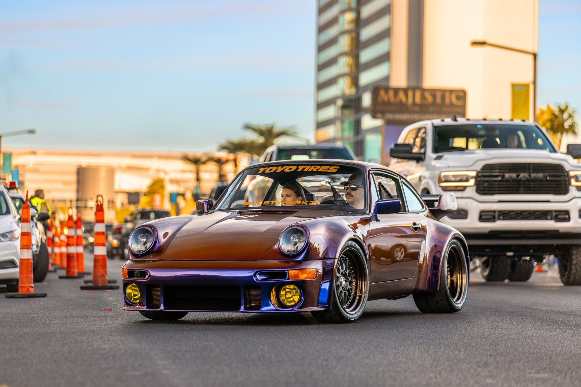 Color shift wrapped RWB Porsche 911 with a Toyo Tires banner and yellow fog lights driving out of the SEMA Show cruise in Las Vegas