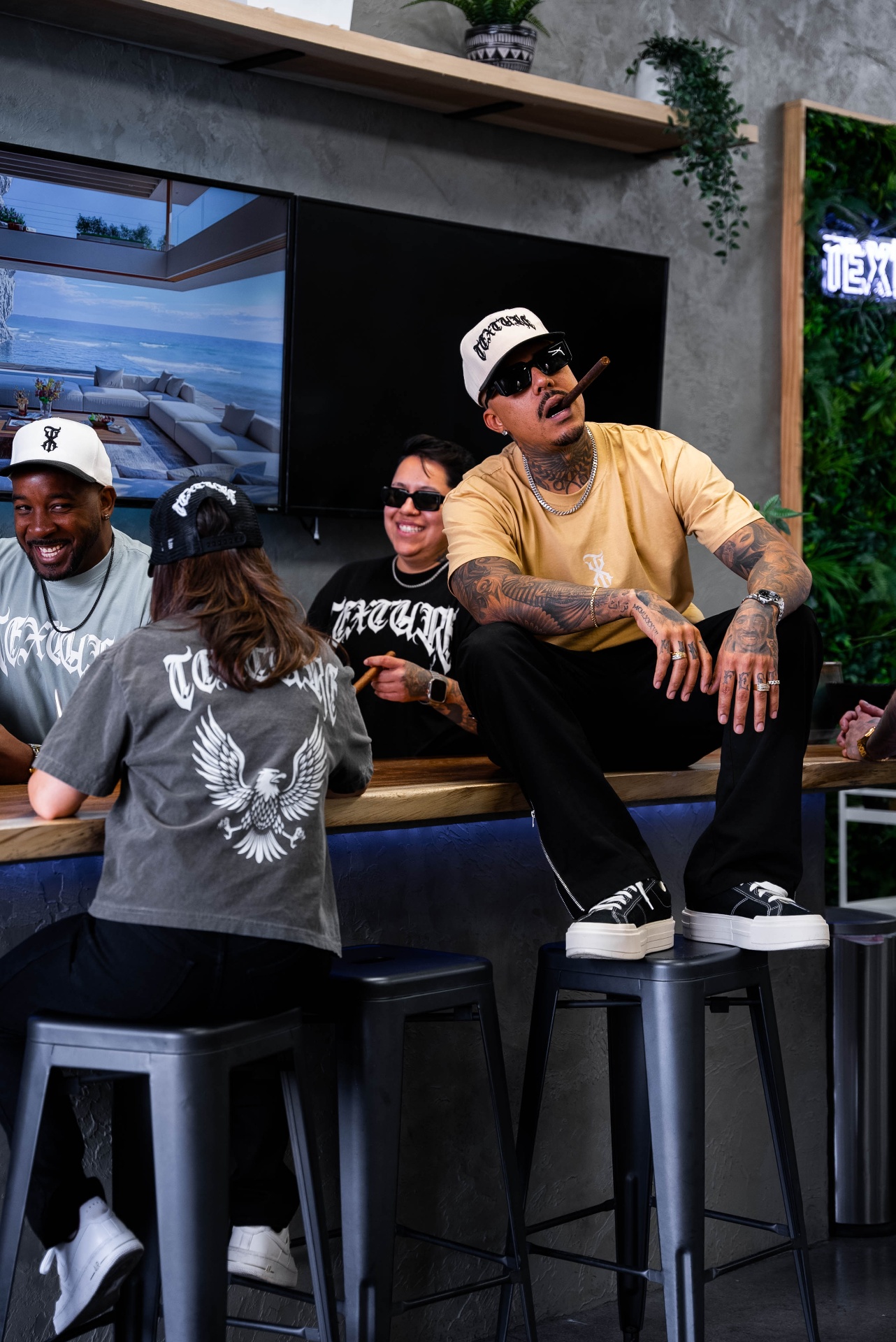 Texture Barbershop team hanging out at the shop's live-edge bar wearing branded apparel, Las Vegas