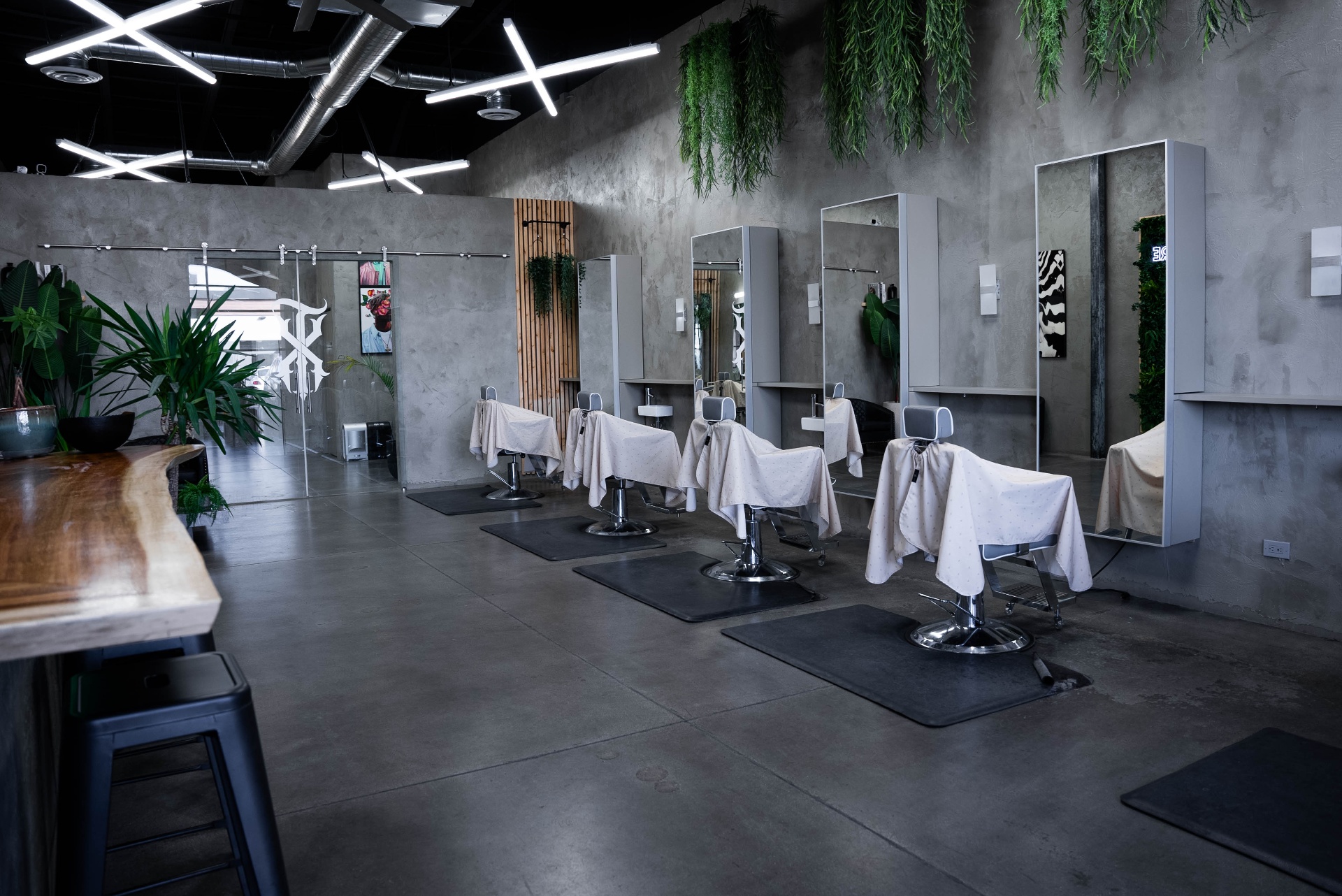 Interior of Texture Barbershop in Las Vegas showing barber chairs, mirrors, and hanging greenery under geometric lighting