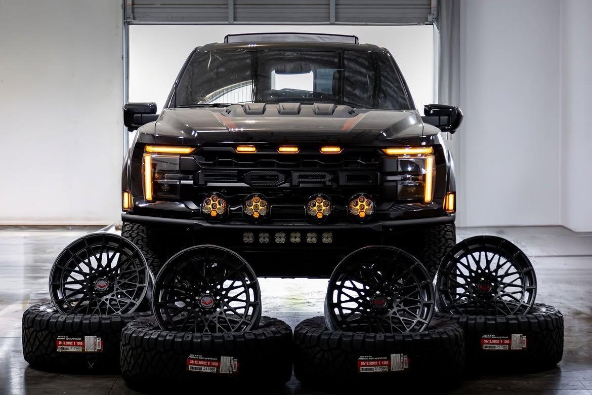 Black Ford Raptor R in a Las Vegas shop bay with four forged wheels and off-road tires staged in front of it